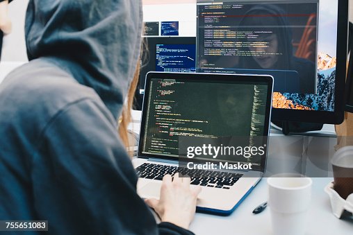 Side View Of Computer Programmer Programming On Laptop At Desk In ...