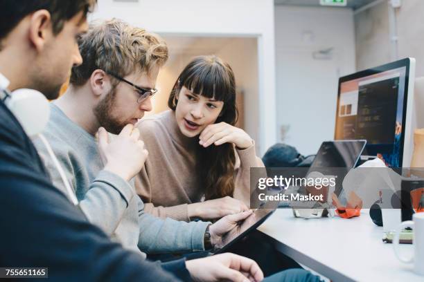 male and female computer programmers discussing over digital tablet at desk in office - webdesigner imagens e fotografias de stock