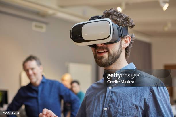 male professional using virtual reality simulator against colleagues at creative office - employee engagement virtual stock pictures, royalty-free photos & images