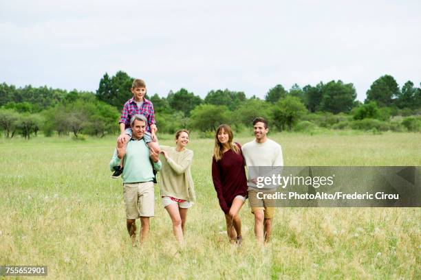 family walking together through field - mid distance stock pictures, royalty-free photos & images