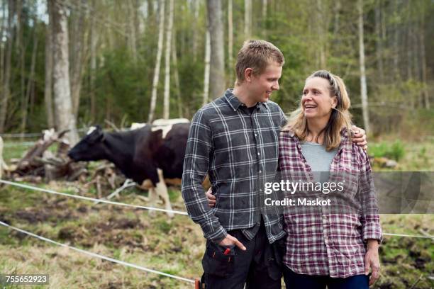 mother and son talking while standing on field - cow cuddling stock pictures, royalty-free photos & images