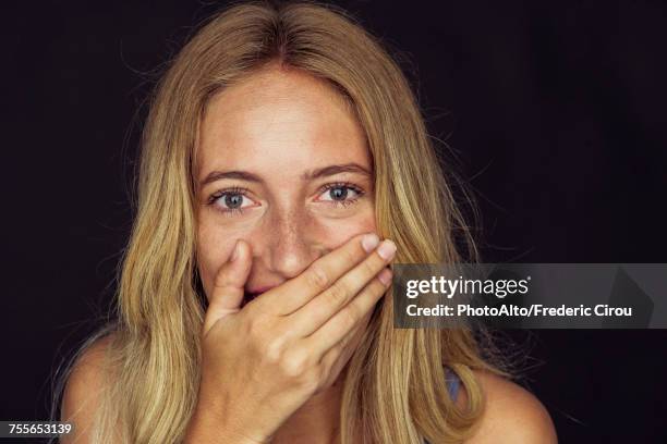 young woman laughing with hand over mouth - shocked woman foto e immagini stock