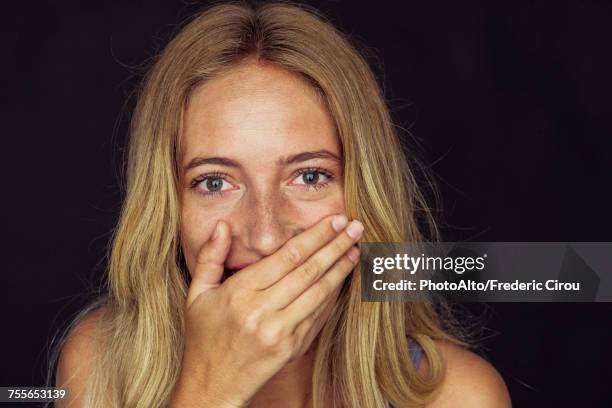 young woman laughing with hand over mouth - mão na boca imagens e fotografias de stock