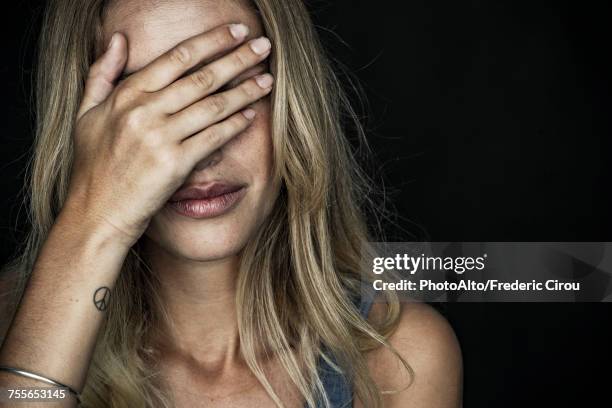 woman covering face with hand - bedauern stock-fotos und bilder