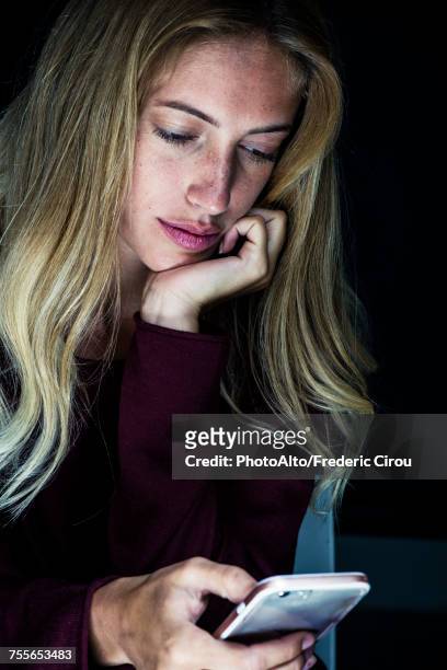 young woman looking at smartphone - studio shot lonely woman stock pictures, royalty-free photos & images
