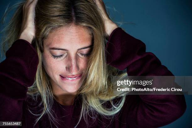 upset young woman holding hand and biting lips - hand in den haaren stock-fotos und bilder