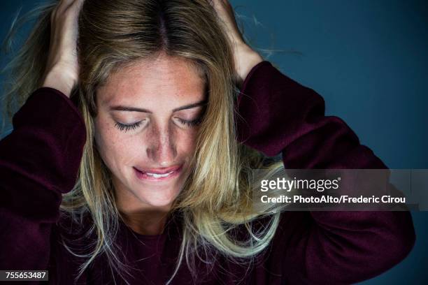 upset young woman holding hand and biting lips - female biting lips stockfoto's en -beelden