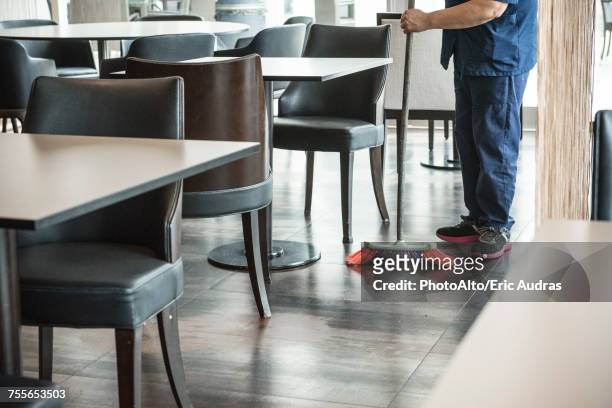 man sweeping restaurant floor - bidello foto e immagini stock