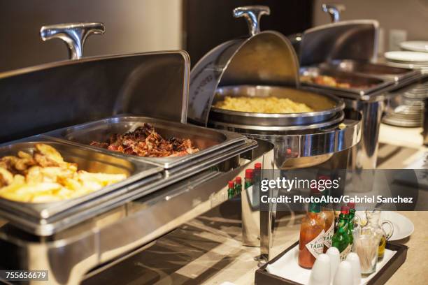 prepared food in warming dishes on buffet - buffet stockfoto's en -beelden