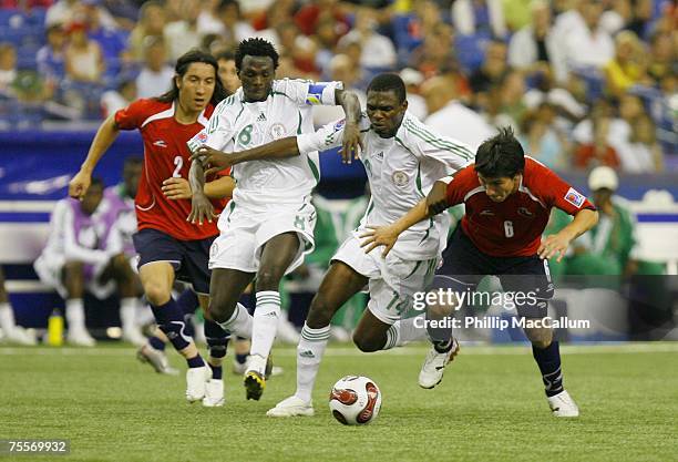 Gary Medel and Christian Suarez of Chile battle for the ball with Chukwuma Akabueze and Ezekiel Bala of Nigeria during the Quaterfinal match of the...