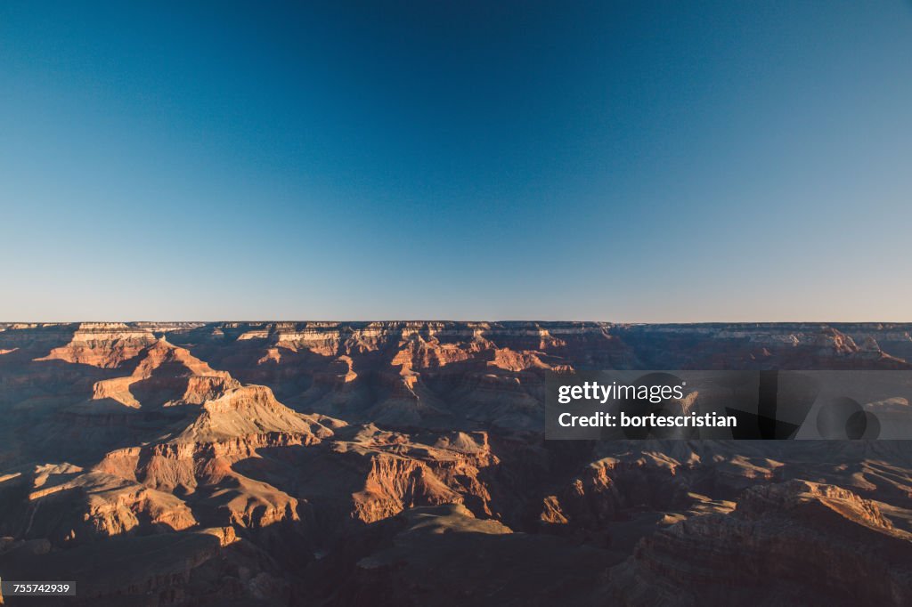 Scenic View Of Eroded Landscape Against Clear Blue Sky During Sunset