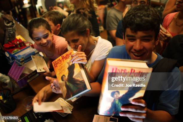 Gabi Maseda, Annie Cardelle and Mike Maseda pick up their new copies of "Harry Potter and the Deathly Hallows" after it went on sale at Books and...