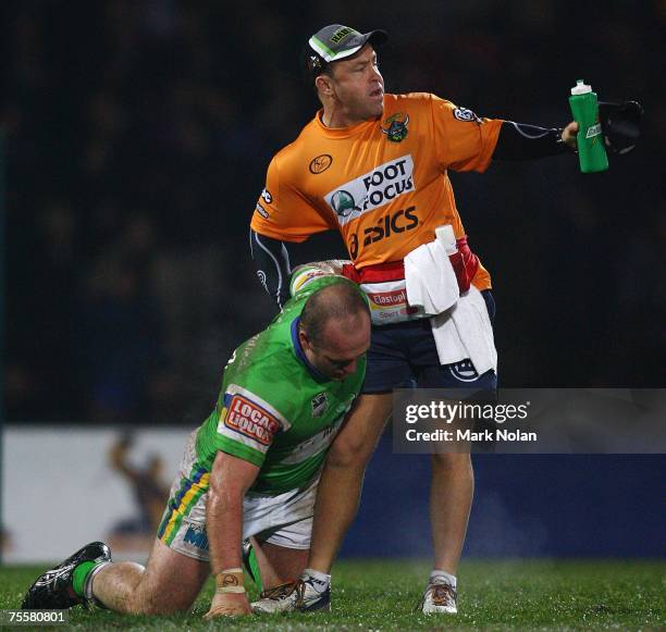 Michael Weyman of the Raiders gets assistance from a trainer after a heavy clash with Jeff Lima of the Storm during the round 19 NRL match between...