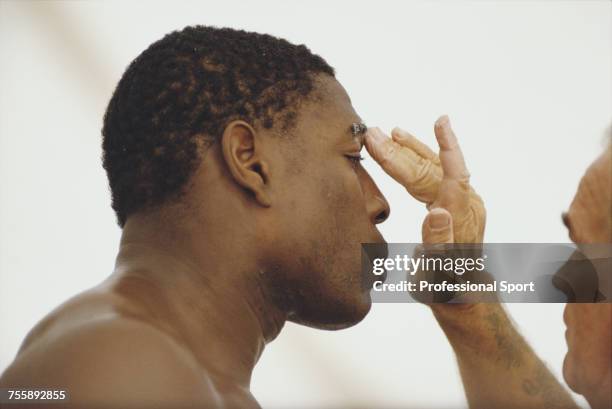 English heavyweight boxer Frank Bruno pictured having protective cream applied to hie eyebrow by his trainer George Francis during a training session...