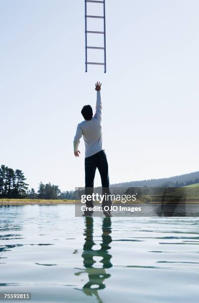 man standing on water reaching for ladder rear view - reiken stockfoto's en -beelden