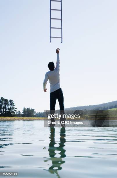 man standing on water reaching for ladder rear view - out of reach stock pictures, royalty-free photos & images