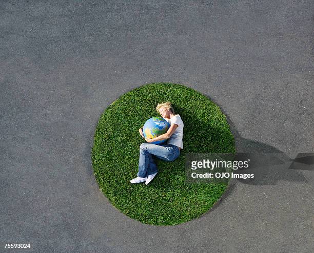 frau liegen in einem kreis gras mit welt auf asphalt - frau globus stock-fotos und bilder