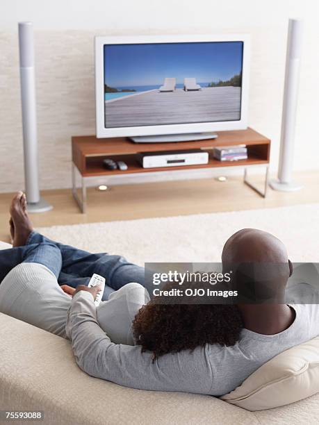 a couple watching television relaxing - family watching tv from behind stock pictures, royalty-free photos & images