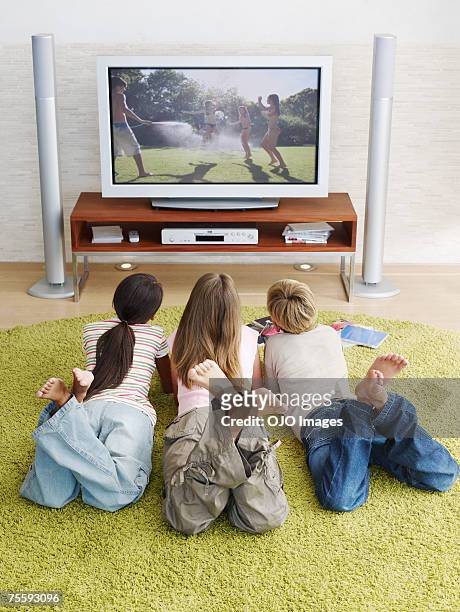 tres jóvenes los niños mientras ve la televisión - familia viendo tv fotografías e imágenes de stock