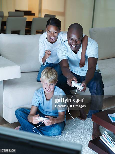 man and two young kids playing a video game - family game night stock pictures, royalty-free photos & images