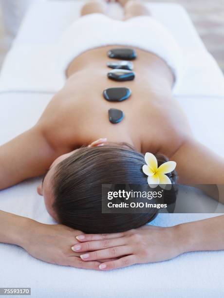 woman relaxing with massage stones on her back - massage therapy stock pictures, royalty-free photos & images