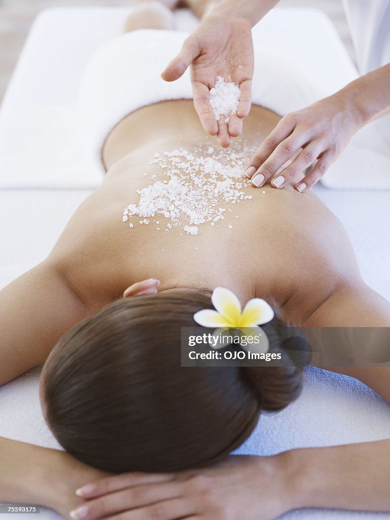 Masseuse applying massage salts to a woman's back
