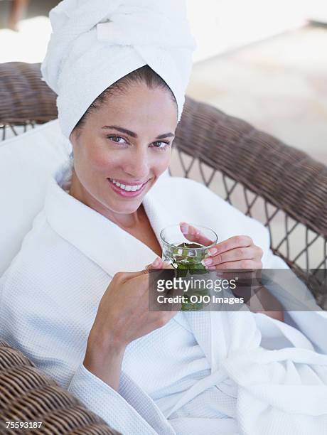woman relaxing in a bathrobe holding a health drink - premium tea bildbanksfoton och bilder