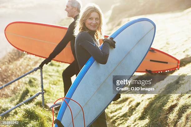 un homme et une femme avec des planches de surf - jeune d'esprit photos et images de collection