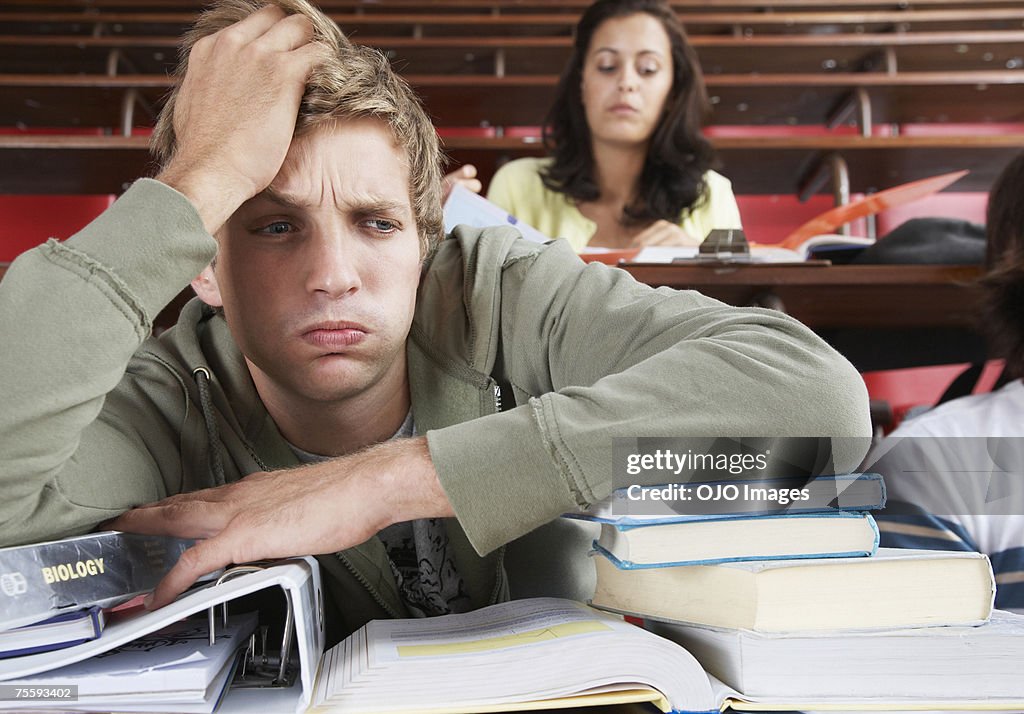 A frustrated male in a classroom with two students in background