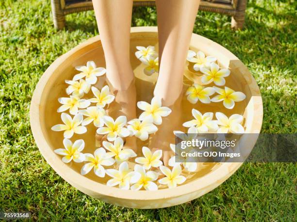 mujer cuadrados de espacio para relajarse en un tazón de agua y flores - legs in water fotografías e imágenes de stock