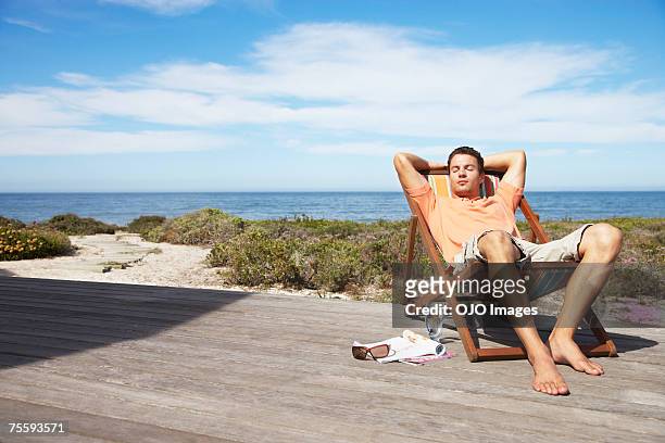 man relaxing in a lounge chair - zonnestoel stockfoto's en -beelden