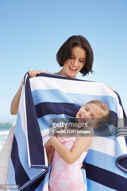 una madre arrollamiento su hija en una toalla de playa - mother daughter towel fotografías e imágenes de stock