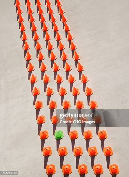 one green pylon amid seventy-four orange pylons - split road sign stock pictures, royalty-free photos & images