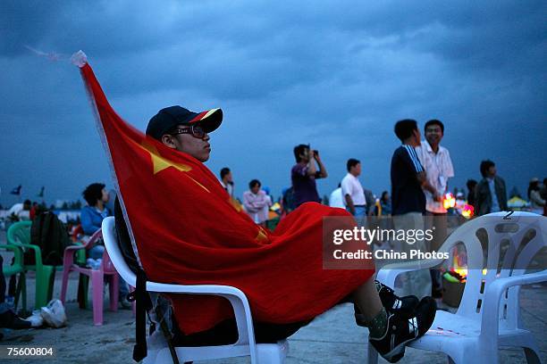 Fan wraps himself with a Chinese national flag at the first "Green Flag - Erdos Grassland Rock Music Festival" near the Mausoleum of Genghis Khan on...