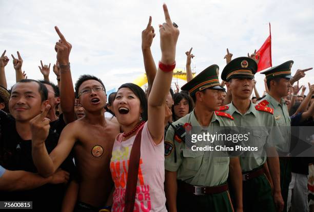 Fans gesture during a performance at the first "Green Flag - Erdos Grassland Rock Music Festival" near the Mausoleum of Genghis Khan on July 21, 2007...