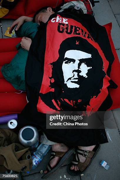 Fan covered by a flag printed with the portrait of revolutionary Che Guevara, sleeps at the first "Green Flag - Erdos Grassland Rock Music Festival"...