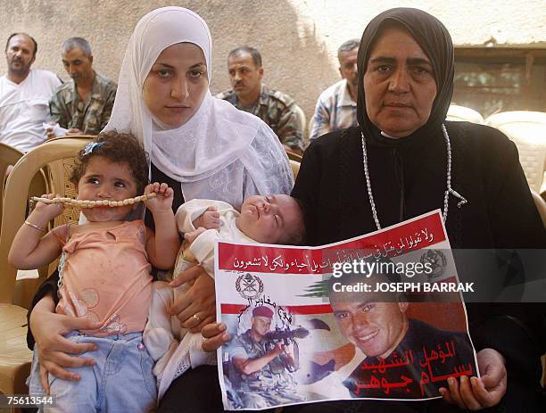 Mariam widow of Lebanese soldier Bassam Jawhar, carries their daughters 50-day-old Fatima and 1-year-old Acil, as his mother Fatima carries his...