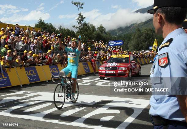 Kazakhstan?s Alexandre Vinokourov celebrates as he crosses the finish line as a policeman looks on at the end of the 15th stage of the 94th Tour de...