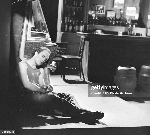 American actor Robert Duvall sits on the floor, slumped against a jukebox, in a scene from an episode of 'Robert Herridge Theater' entitiled 'The...