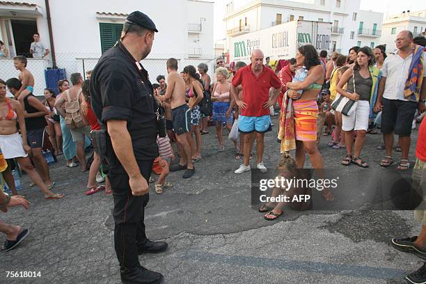 Carabiniere looks at beachgoers evacuated from beaches hit by the blazes near Peschici, 24 July 2007.Wildfires claimed four lives in southern Italy's...