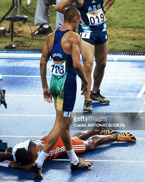 Rio de Janeiro, BRAZIL: Brazilian runner Carlos Chinin passes by Cuban Yordan Garcia, who rests on the floor, at the end of the 1500 race 24 July...