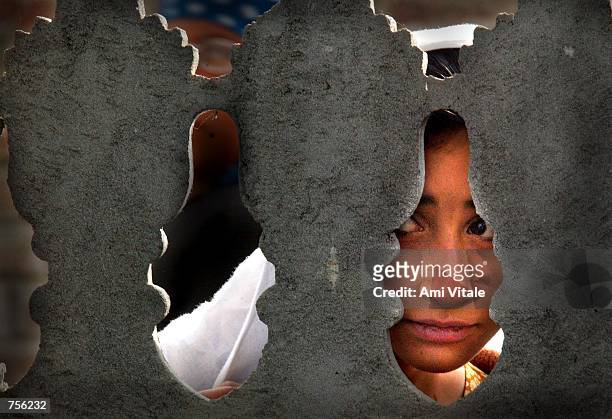 Kashmiri woman looks through a fence outside a graveyard April 3, 2002 to try and see an unidentified youth who was found killed in the streets of...