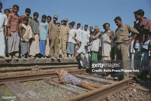 View of Indian army troops and local civilians looking at the bound body of a man found shot on a railway line near the East Pakistan town of Jessore...