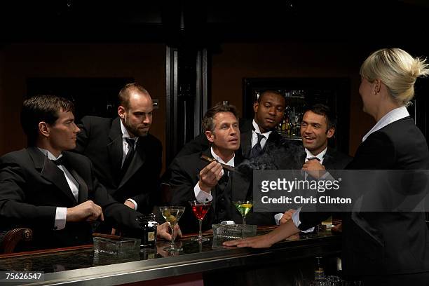 men in dinner jackets drinking cocktails in bar, one holding cigar - smoking cigar fotografías e imágenes de stock