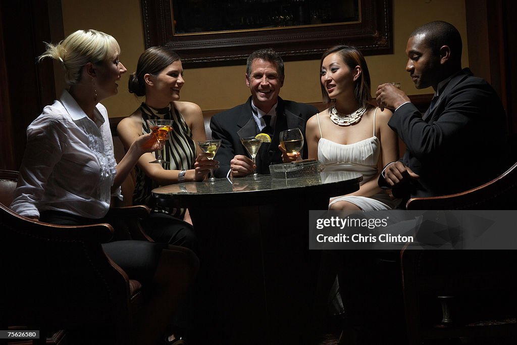 Men and women sitting round table with drinks, upper half