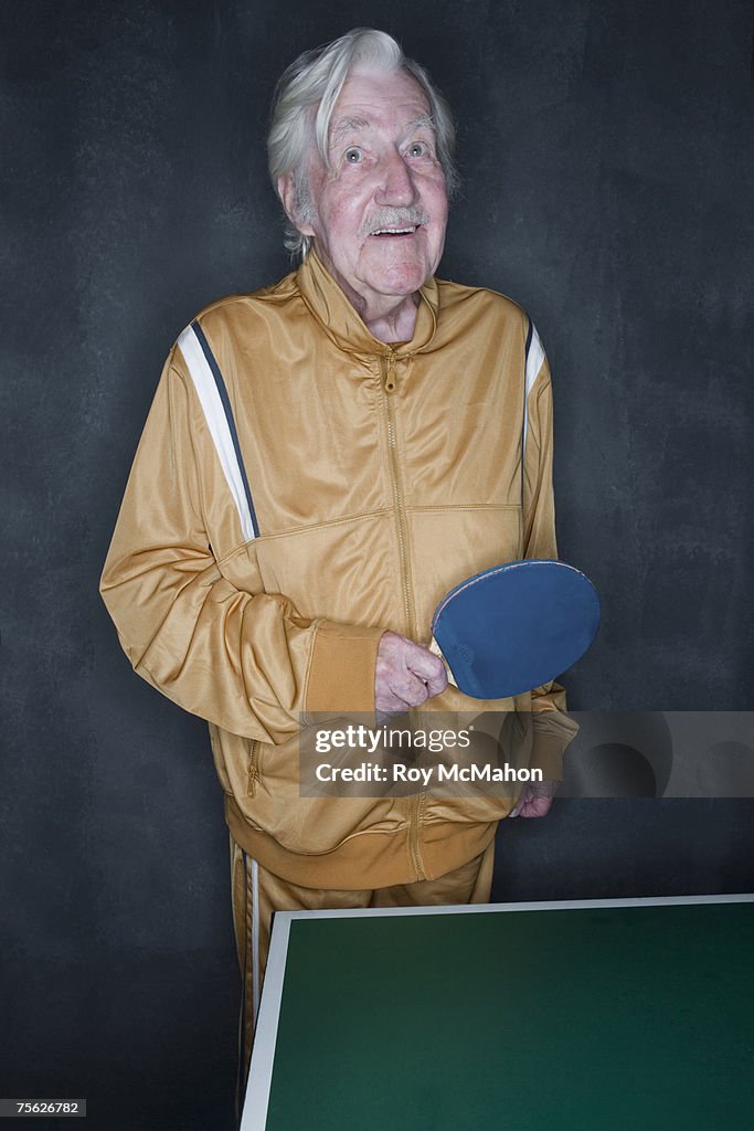 Senior man playing table tennis, upper half