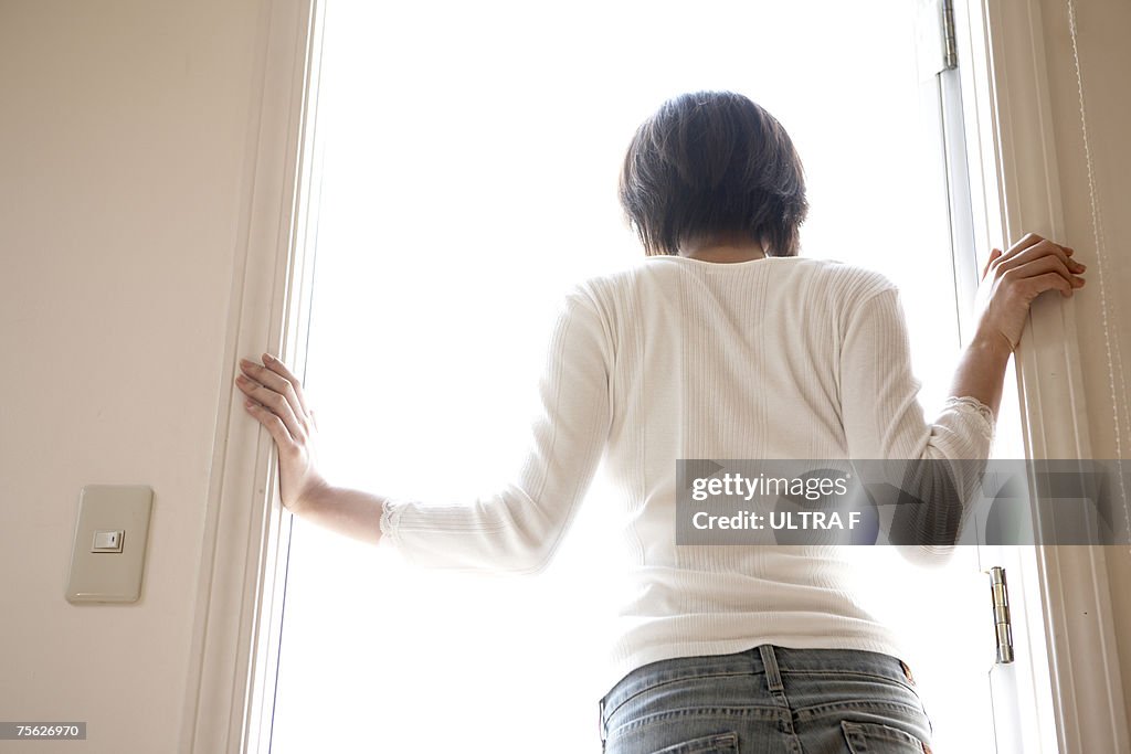 Woman standing in doorway of home, rear view