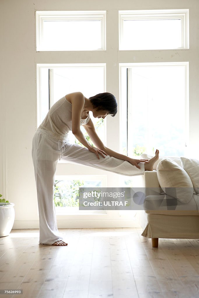 Young woman stretching legs on sofa in living room