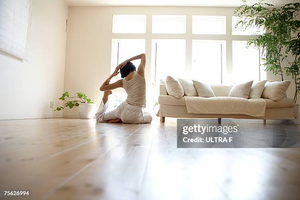 young woman performing yoga pose in living room - yoga poses for f stock pictures, royalty-free photos & images