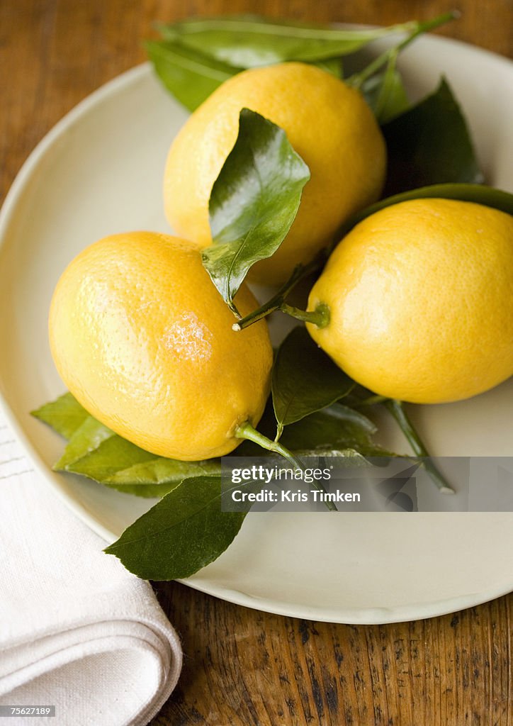 Three lemons on plate, high angle view